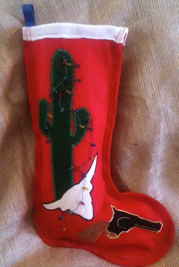 A red felt stocking with a cactus, a skull, and a six-shooter