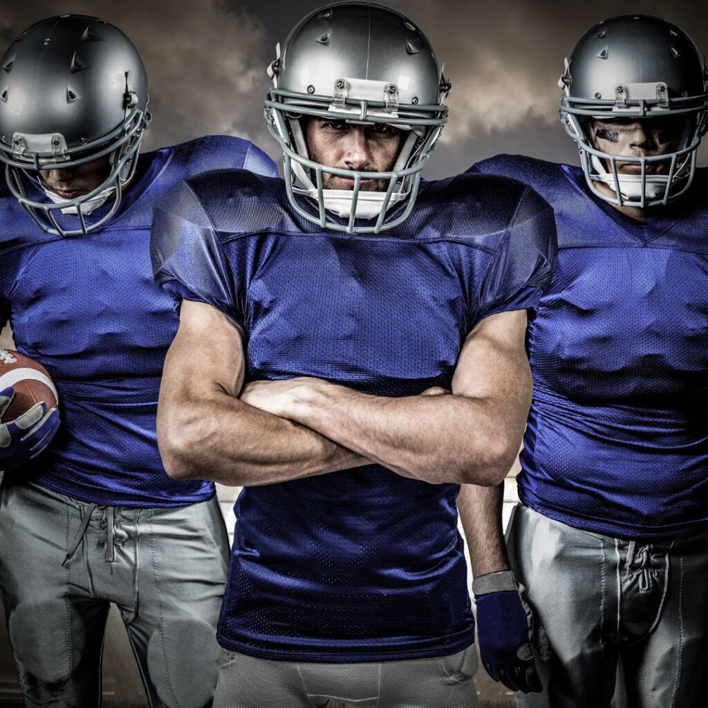 3 football players wearing helmets and blue shirts