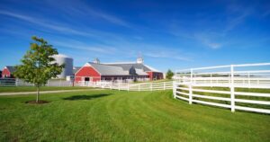 A farm with a Red Barn, green grass, and white fences. Meadow Lane Farm
